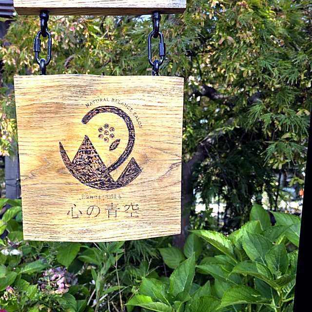 庭に下げた、ロゴ入りの木の看板